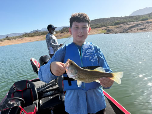Young angler with catch on lake